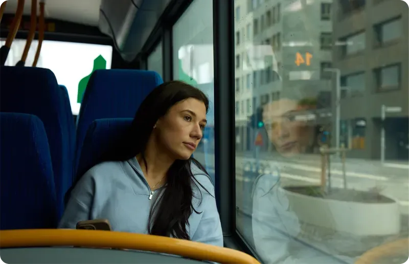Einstaklingur horfir út um glugga í strætó