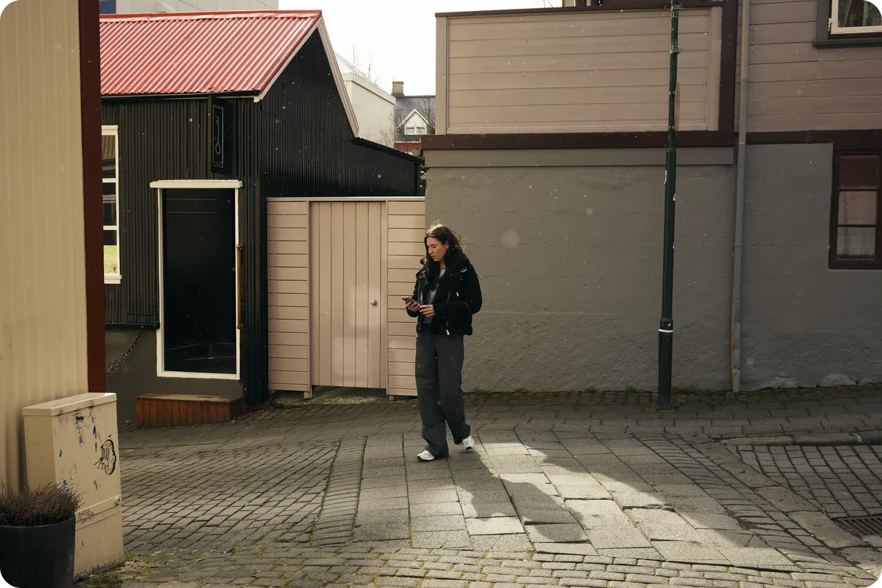 Someone walks along a cobbled street, looking at a phone