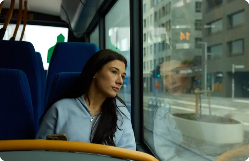 Einstaklingur horfir út um glugga í strætó